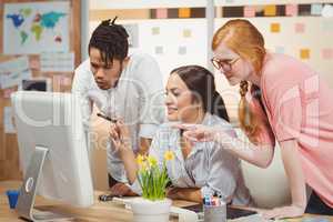 Smiling business people pointing towards computer in office