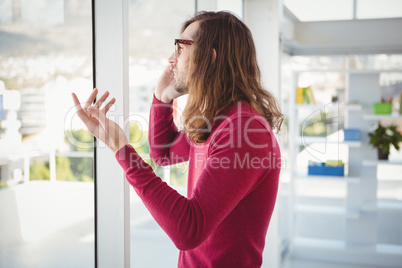 Hipster talking on cellphone standing by window