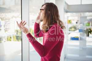 Hipster talking on cellphone standing by window