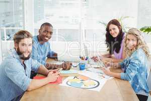 Portrait of smiling business people working while sitting at des