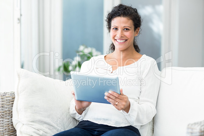 Portrait of happy woman using tablet on sofa