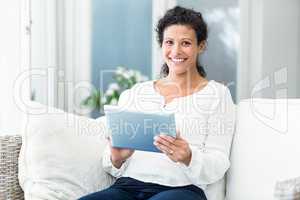 Portrait of happy woman using tablet on sofa