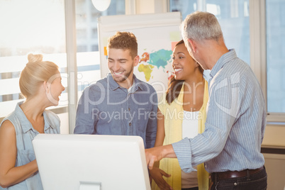 Smiling business people using computer in meeting room