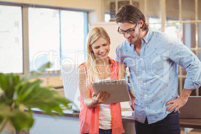 Businesswoman showing something to male colleague on digital tab