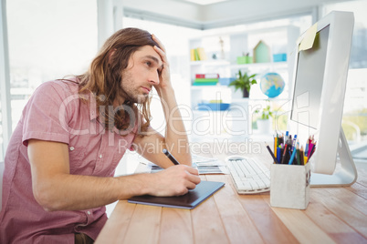 Tired hipster working on graphics tablet and computer