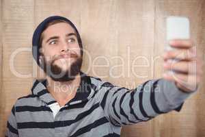 Hipster making face while taking selfie on mobile phone