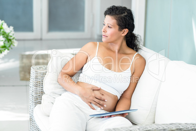 Happy woman sitting on sofa with tablet