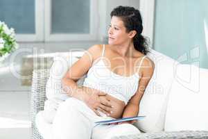 Happy woman sitting on sofa with tablet
