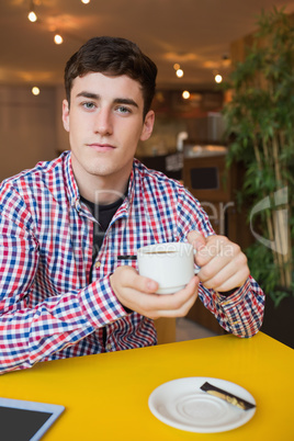 Young man holding coffee cup at cafe