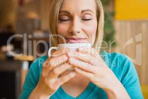 Young woman holding coffee cup with eyes closed