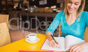 Happy young woman writing on book