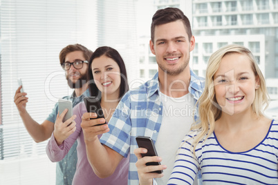 Portrait of smiling business people using smartphones while stan