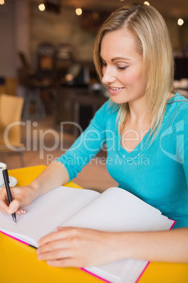 Close-up of happy young woman writing on book