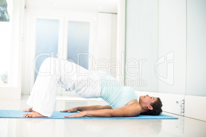 Pregnant woman lying on floor in bridge pose