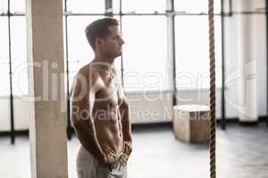 Muscular shirtless man posing in crossfit gym