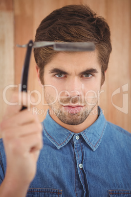 Portrait of hipster holding straight edge razor