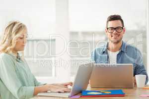 Portrait of happy man wearing eyeglasses with woman working on l
