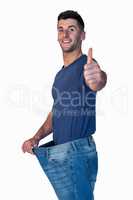 Portrait of a man showing thumbs up while stretching jeans