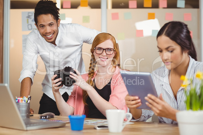 Colleagues holding camera with businesswoman using digital table