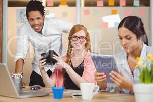 Colleagues holding camera with businesswoman using digital table