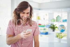 Hipster smiling while looking at mobile phone