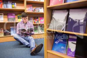 Young man reading book while sitting on floor
