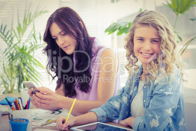 Portrait of smiling woman while sitting at desk with coworker