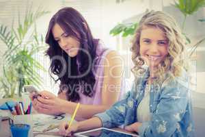 Portrait of smiling woman while sitting at desk with coworker