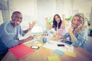 Portrait of smiling business people gesturing while sitting at d