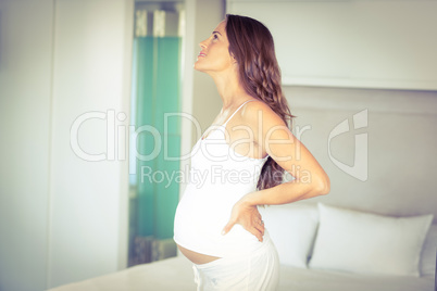 Side view of pregnant woman standing in bedroom