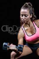 Serious fit woman lifting dumbbell
