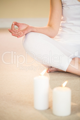 Low section of meditating woman with illuminated candles