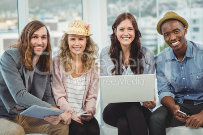 Portrait of smiling business people with laptop and digital tabl