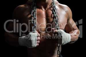 Midsection of muscular man holding chain