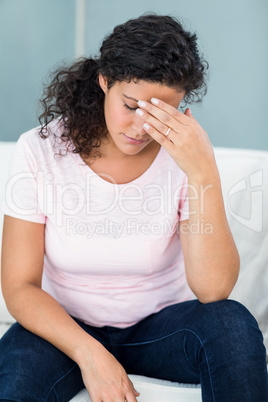 Tired pregnant woman sitting on sofa