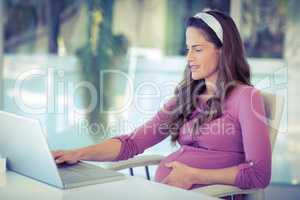 Pregnant businesswoman working on laptop