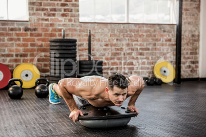 Shirtless man doing bosu push ups