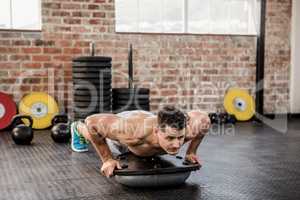 Shirtless man doing bosu push ups