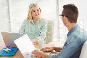 Smiling woman looking at man while sitting on chair