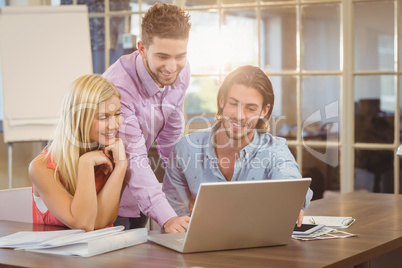 Smiling businessman using laptop while colleagues