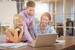 Smiling businessman using laptop while colleagues