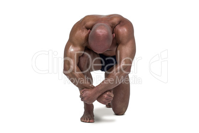 Muscular man bending on knee