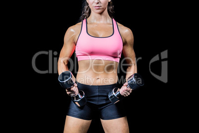 Midsection of woman exercising with dumbbells