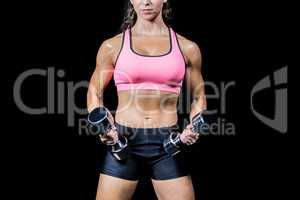 Midsection of woman exercising with dumbbells