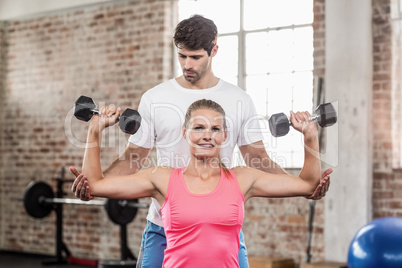 Fit woman lifting dumbbells with trainer