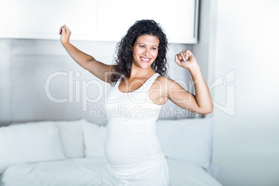 Beautiful pregnant woman stretching in bedroom