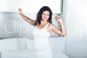 Beautiful pregnant woman stretching in bedroom