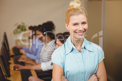 Businesswoman with arms crossed standing against employees