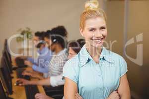 Businesswoman with arms crossed standing against employees