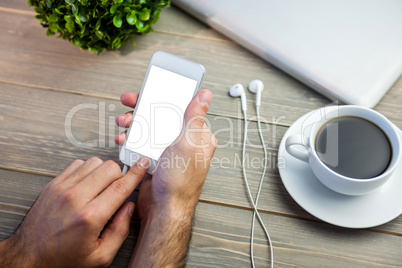 Person using smart next to coffee mug at desk